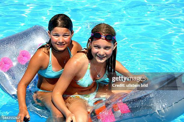 Kinder auf einer Luftmatraze in einem Schwimmbad