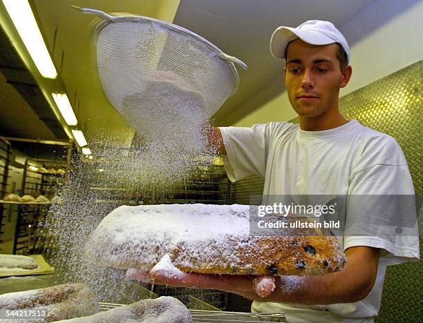 Deutschland, Ruegener Backwaren GmbH Bergen: Baecker pudert einen Christstollen in der Backstube