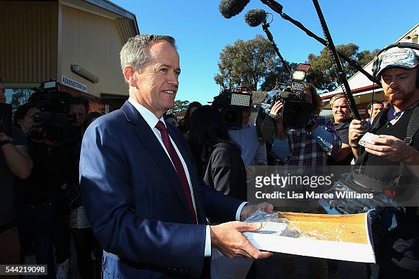 Opposition Leader, Australian Labor Party Bill Shorten hands out lamingtons to the media during a visit to a polling booth at Colyton on July 2, 2016...
