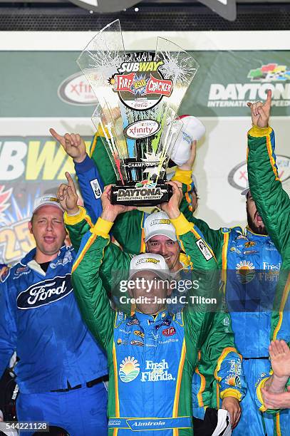 Aric Almirola, driver of the Fresh From Florida Ford, raises the winner's trophy in Victory Lane after winning the NASCAR XFINITY Series Subway...
