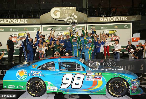 Aric Almirola, driver of the Fresh From Florida Ford, raises the winner's trophy in Victory Lane after taking the checkered flag in the NASCAR...