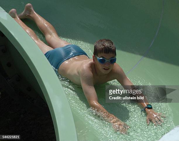 Junge auf einer Wasserrutsche im Schwimmbad
