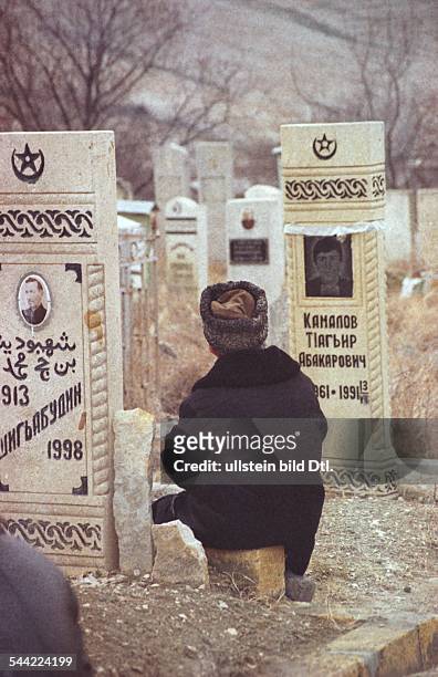 Russland, Tschetschenien - tschetschenische Maenner auf einem Friedhof in Grosny - Maerz 2004