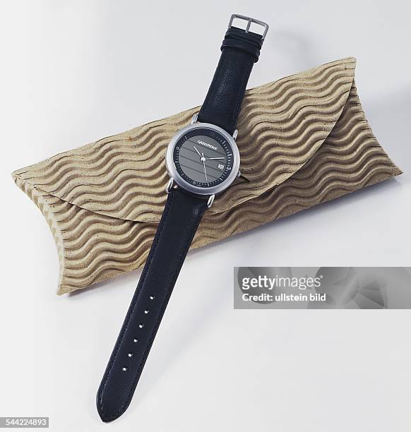 Armbanduhr mit schwarzem Lederarmband und der Aufschrift GREENPEACE, swiss made, liegt auf einem Etui