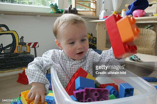 Spielzeug, Kleiner Junge spielt im Kinderzimmer mit grossen Lego Steinen fuer Kleinkinder