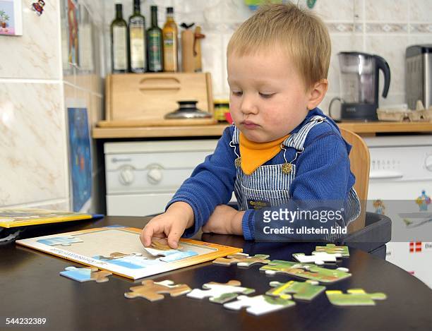 Kleiner Junge spielt mit einem Puzzle am Küchentisch