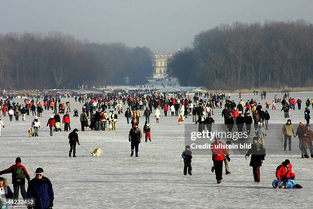 Deutschland, Bayern: Menschen auf dem zugefrorenen Chiemsee vor der Insel Herrenchiemsee.