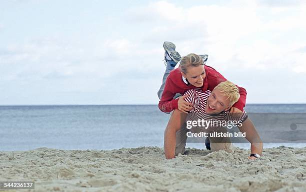 Ein junges Paar tobt miteinander am Strand von Binz auf der Insel Ruegen in Mecklenburg Vorpommern.