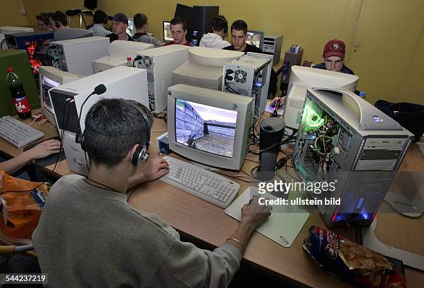 Jugendliche bei einer LAN Party mit Computerspielen. Duch Vernetzung der Computer koennen mehrere Spieler gegeneinander spielen.