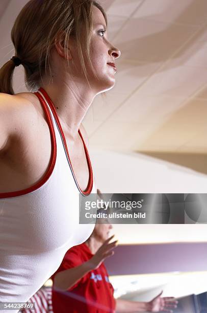 Junge Frau macht Gymnastik in der Gruppe unter Anleitung