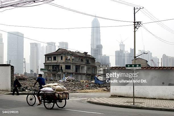 China, Shanghai: Mann mit Lastenfahrrad vor einem Abrissgebiet.