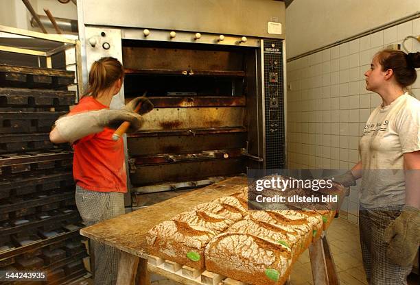 Arbeiten in der Backstube, hier wird das fertige Brot aus dem Ofen gezogen