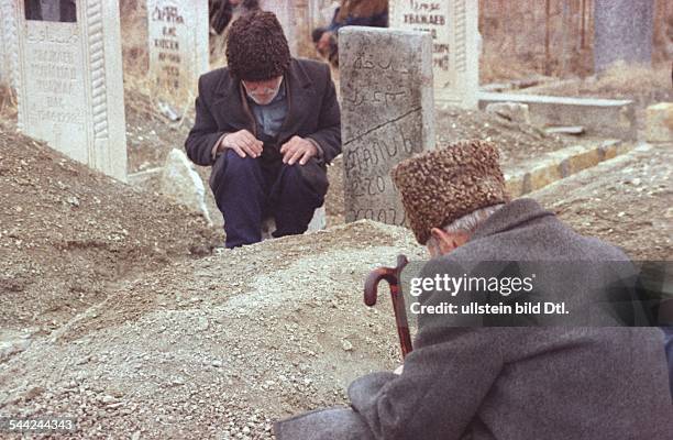 Russland, Tschetschenien - tschetschenische Maenner auf einem Friedhof in Grosny - Maerz 2004