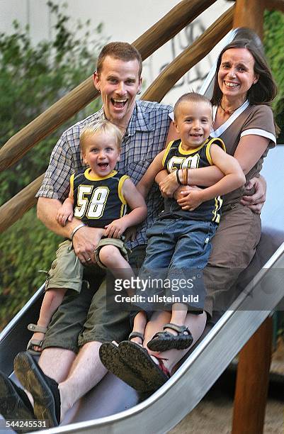 Familienleben: Familie mit zwei Kindern auf einer Rutsche-
