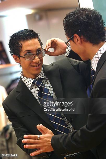 Junger Mann, suedlaendischer Typ, mit Anzug, Krawatte, Gelfrisur und grosser Sonnenbrille, betrachtet sich im Spiegel - 2003