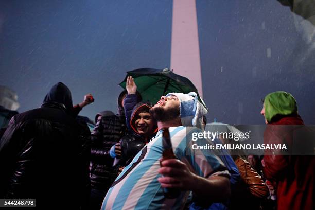 Fans of Argentine football star Lionel Messi rally under the rain asking for his return to the national team at the Obelisco in Buenos Aires on July...