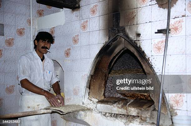 Iran, Shiraz: Mann in einer Baeckerei, in der das typische persische Brot, ein duennes Fladenbrot, im Ofen auf Kieselsteinen gebacken wird.