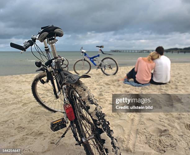 Ein junges Paar sitzt am Strand von Binz auf der Insel Ruegen in Mecklenburg Vorpommern-