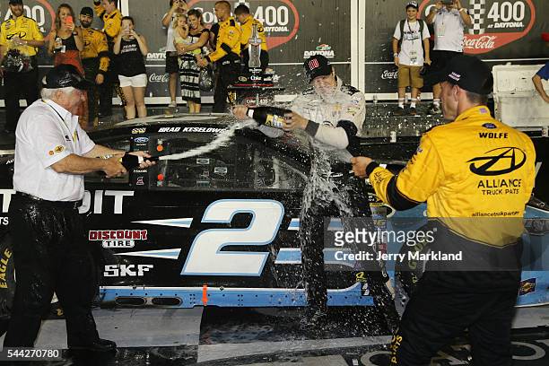 Brad Keselowsk driver of the Detroit Genuine Parts Ford, celebrates with champagne in Victory Lane with team owner Roger Penske and crew chief Paul...