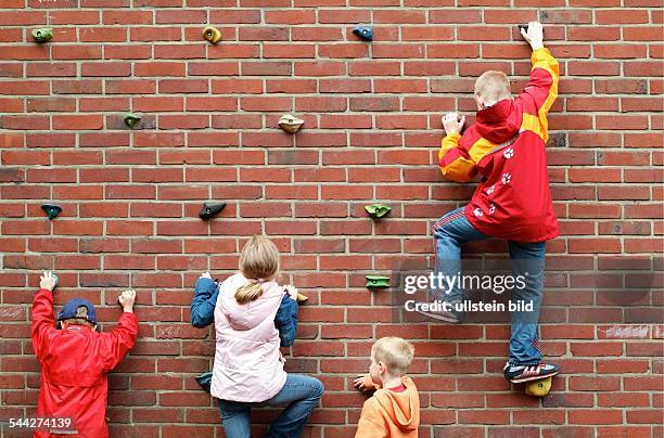 Deutschland, Kinder klettern an einer Kletterwand an der Aussenwand einer Grundschule