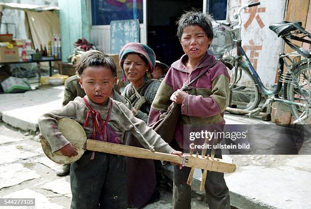 Tibet, Lhasa: Kleiner Junge mit Schnupfnase spielt stolz auf seiner Gitarre.