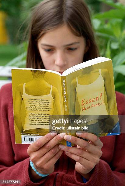 Essstörungen, Magersucht, Mädchen liest das Buch "Essen? Nein Danke!"