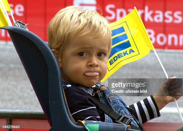 Kleiner Junge mit Werbefaehnchen von EDEKA im Kindersitz eines Fahrrads-