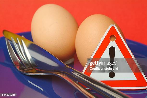 Symbol Vogelgrippe, Salmonellen, Schadstoffe in Lebensmitteln, Eier, Besteck und Warnschild auf einem Teller