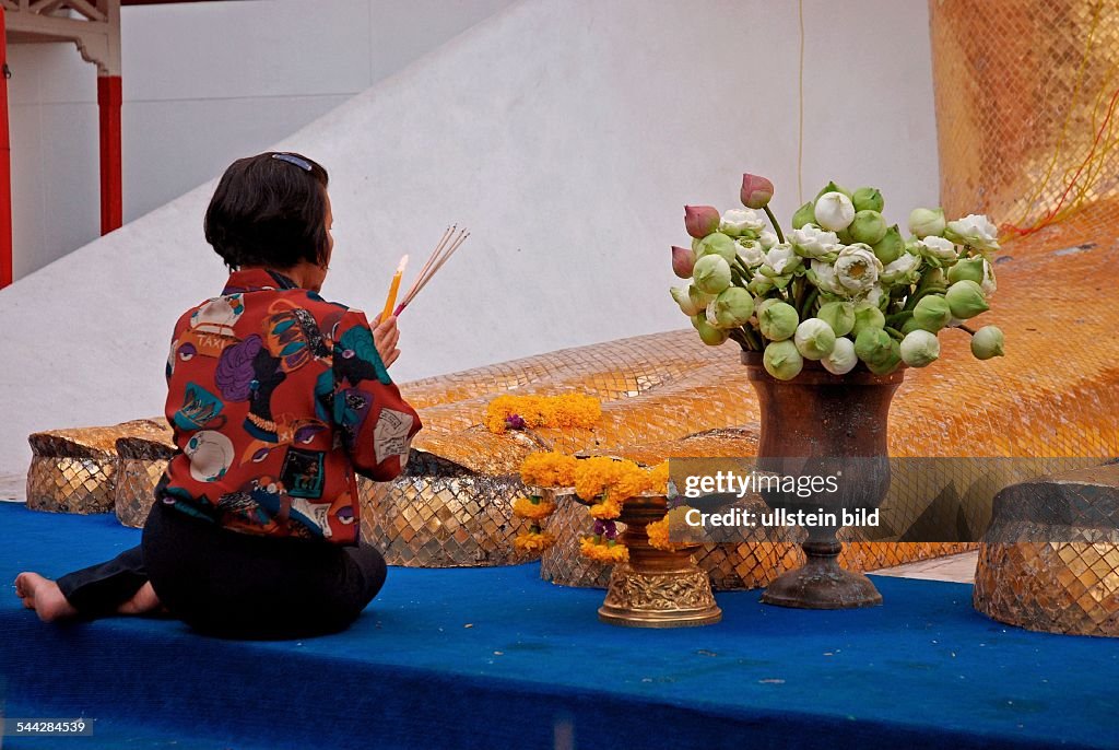 Glaeubige Buddhistin vor einer Buddhastatue