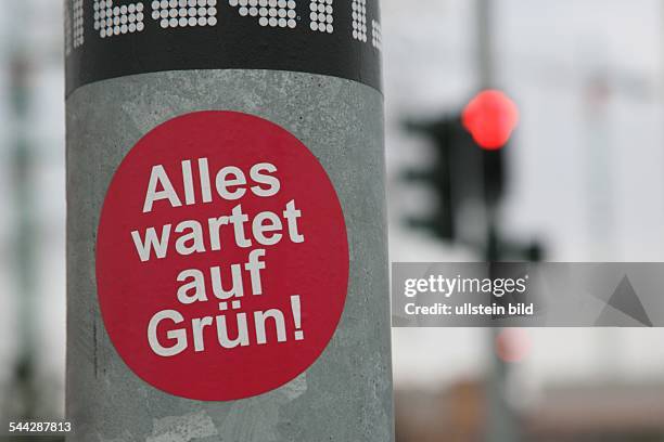 Deutschland, Berlin: Mitte, Aufkleber an einer Ampel mit dem Schriftzug "Alles wartet auf Gruen!", im Hintergrund eine rote Fußgaengerampel