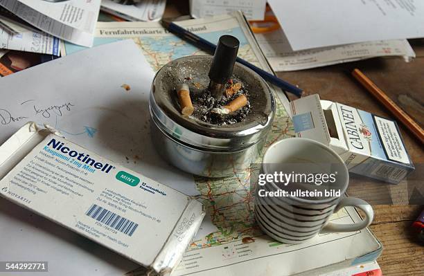 Büro, Chaos auf dem Schreibtisch, leere Zigarettenschachtel, Nicotinell Kaugummis zum Abgewoehnen des Rauchens neben einem vollen Aschenbecher und...