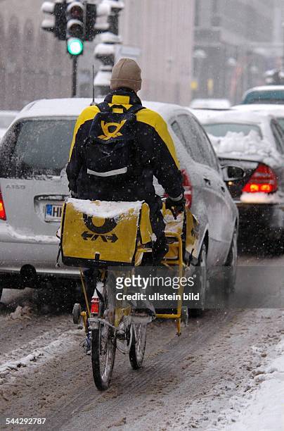 Deutschland, Berlin, Post, Postbote auf dem Fahrrad bei Schnee