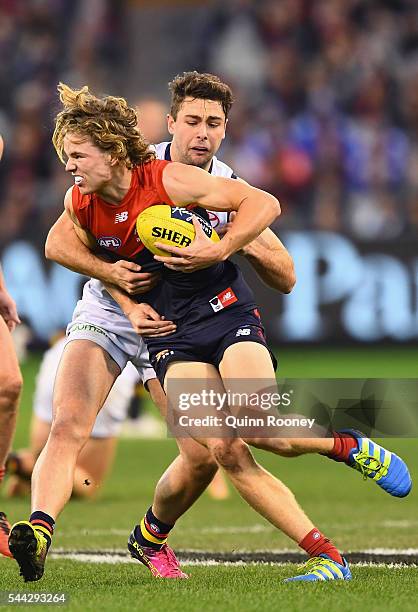 Jayden Hunt of the Demons is tackled by Rory Atkins of the Crows during the round 15 AFL match between the Melbourne Demons and the Adelaide Crows at...