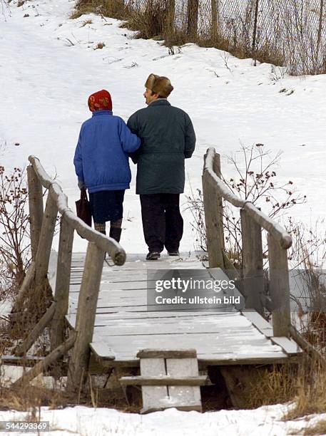 Weissrussland - Mann mit Schapka und eine Frau mit rotem Kopftuch bei einem Spaziergang - Februar 2005