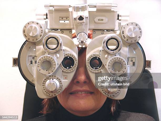 Augenarzt, Augenkrankheiten, Sehschwaeche: Patientin beim Augenarzt , Optiker mit Geraet zum Anpassen einer Brille