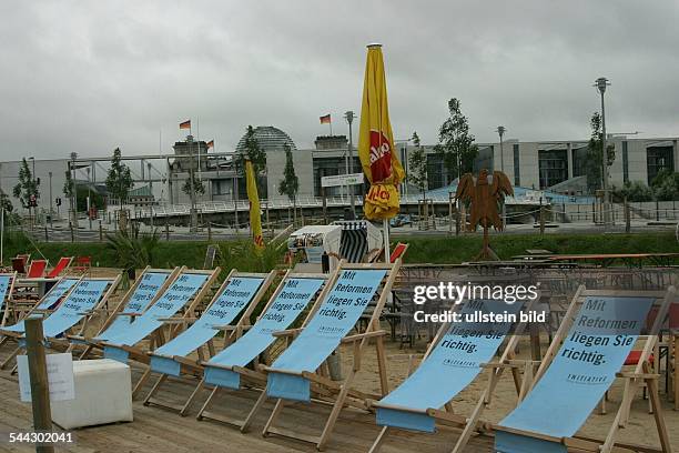 Deutschland, Berlin - Mitte: Regenwetter am Bundespressestrand. Leere Liegestuehle mit der Aufschrift "Mit Reformen liegen Sie richtig". Im...