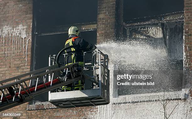 Brand in einer Fabrikhalle, Feuerwehrmann auf einer Drehleiter löscht mit Löschschaum