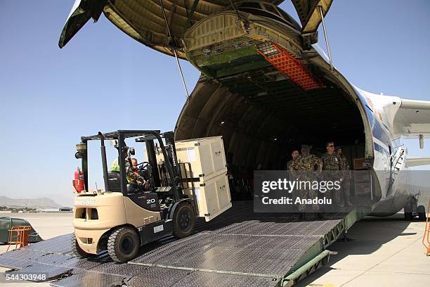 Afghan military personal unload the military assist packages from a cargo plane during the handover ceremony as China delivers first shipment of...