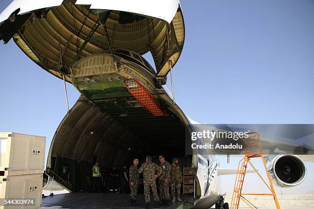 Afghan military personal unload the military assist packages from a cargo plane during the handover ceremony as China delivers first shipment of...