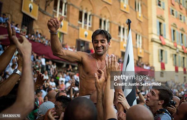 The jockey, Jonatan Bartoletti aka 'Scompiglio' of the 'Contrada of Lupa' is carried on his contrada members shoulders after winning the historical...