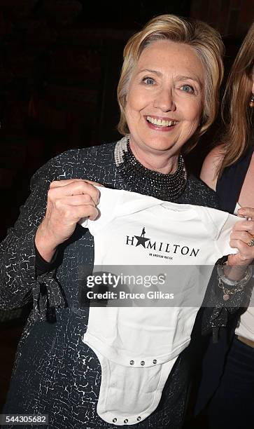 Hillary Clinton poses with a "Hamilton" onesie for grandson Aiden Mezvinsky backstage at the hit musical "Hamilton" on Broadway at The Richard Rogers...