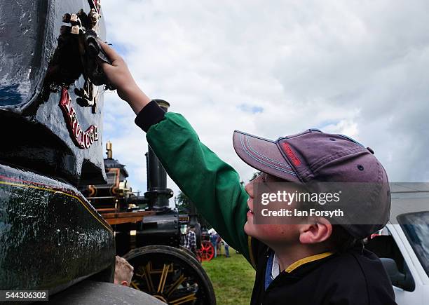 Harry Barker helps to clean the steam engine, the Pride of Harwood at the annual Duncombe Park Steam Fair on July 3, 2016 in Helmsley, England. Held...