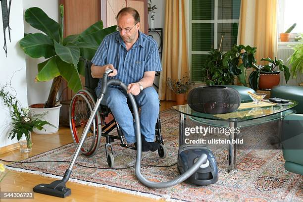 Behinderte, Mann im Rollstuhl beim Staubsaugen in der Wohnung, handicapped person in a wheel chair with a vacuum-cleaner