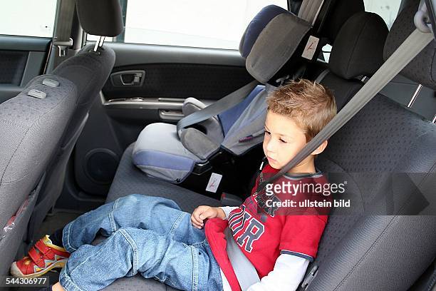 Verkehrssicherheit, Sicherheitsgurt, Kindersitz, Kind sitzt neben dem Kindersitz auf der Rueckbank im Auto