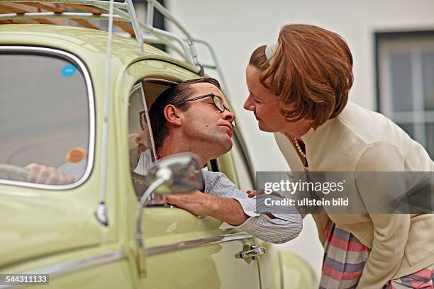 Familienfoto im Stil der 50er-Jahre. Der Volkswagen Baujahr 1955 steht im Mittelpunkt. Szene: Vater, Mutter und drei Kinder posieren stolz vor dem...