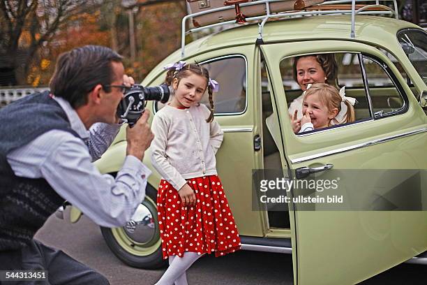 Familienfoto im Stil der 50er-Jahre. Der Volkswagen Baujahr 1955 steht im Mittelpunkt. Szene: Vater, Mutter und drei Kinder posieren stolz vor dem...