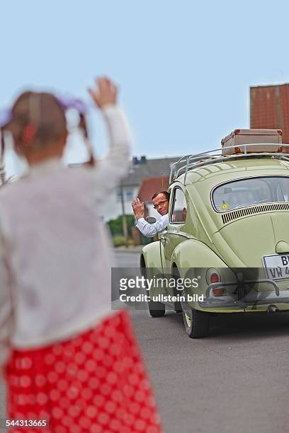Familienfoto im Stil der 50er-Jahre. Der Volkswagen Baujahr 1955 steht im Mittelpunkt. Szene: Vater, Mutter und drei Kinder posieren stolz vor dem...
