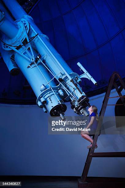 girl looking through a large telescope - observatoire photos et images de collection