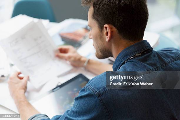 man going over invoices in office - documentos imagens e fotografias de stock