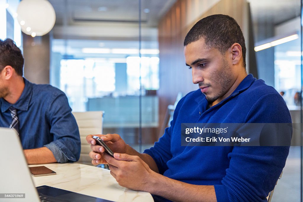 Man reading emails in office on smartphone